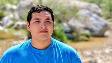 Victor in a blue tshirt in front of a blurred background