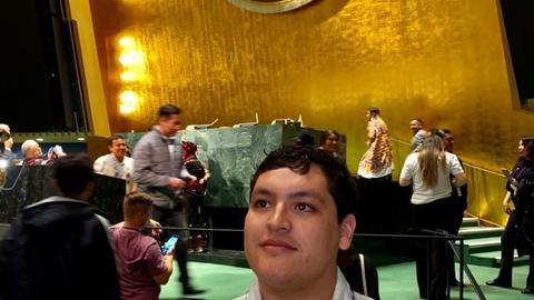 Victor Lopez-Carmen posing for a photo in front of the UN logo
