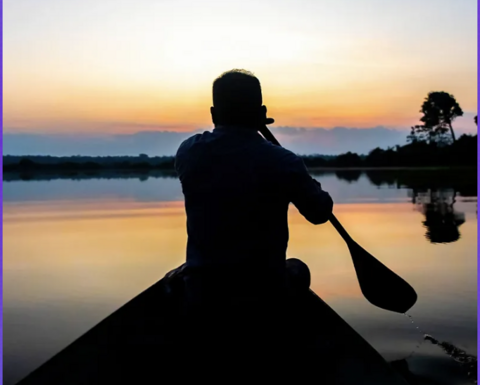 Man rowing in the water during a sunset